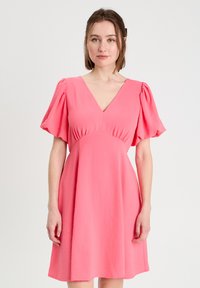 Robe courte rose avec un décolleté en V et des manches bouffantes, présentant une taille cintrée et une jupe évasée. Texture lisse et tissu léger.