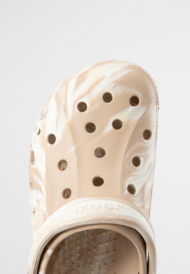 Zuecos de plástico beige con un patrón veteado, que cuentan con múltiples orificios de ventilación, una correa en el talón y una plantilla texturizada.