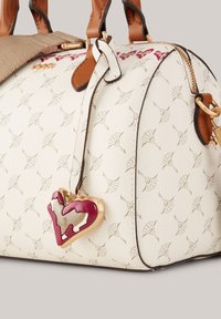 Borsa a mano crema con motivo a rilievo sottile, dettagli in pelle marrone, hardware dorato e un charm a forma di cuore staccabile.