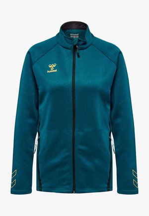 Veste zippée teal en tissu doux, avec un col haut, une fermeture éclair noire, des poches latérales et un logo jaune avec des rayures inclinées sur les manches.