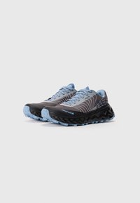 Ein Paar schwarze und hellblaue Trailrunning-Schuhe mit wellenförmigen weißen Linien und dicken strukturierten Sohlen auf einem schlichten weißen Hintergrund.