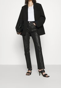 Musta ylipitkä bleiseri, valkoinen sovitettu yläosa, kiiltävät mustat korkeavyötäröiset housut ja mustat korkokenkäsandalsit. Rentoa mutta silti tunnollista tyyliä.