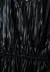 Tissu plissé noir avec une texture brillante. Présente des détails de taille froncée. Le matériau semble doux et lisse, créant des lignes verticales.