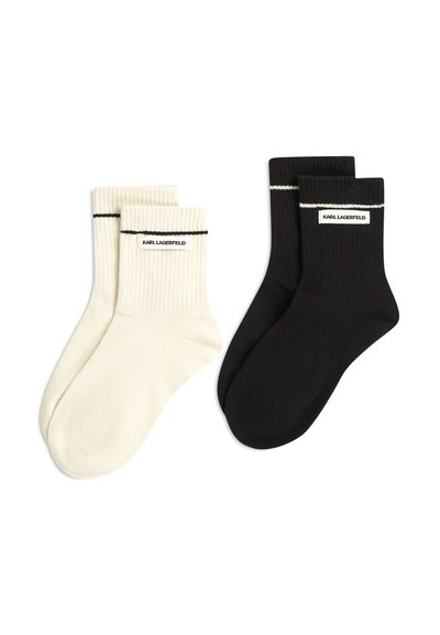 Deux paires de chaussettes côtelées montantes, l'une blanche et l'autre noire, chacune avec une bande noire ou blanche et une étiquette "KARL LAGERFELD" près du bord-côte.
