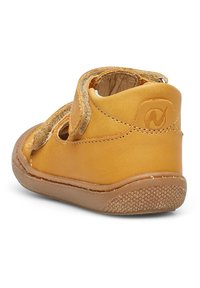 Żółte skórzane buty dla małych dzieci z zaokrąglonym noskiem, teksturowaną podeszwą, rzepem oraz wycięciami po bokach dla lepszej wentylacji.