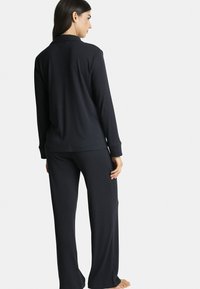 Ensemble de pyjama bleu foncé à manches longues avec une coupe décontractée. Comprend un col, une texture côtelée et un pantalon assorti avec une coupe droite.