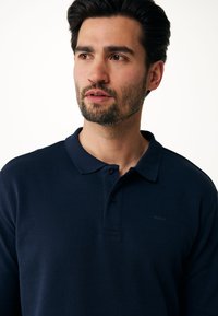 Marineblaue Poloshirt aus strukturiertem Stoff, mit einer drei-Knopfleiste und kleinem Branding auf der Brust. Standardpassform mit klassischem Kragen.