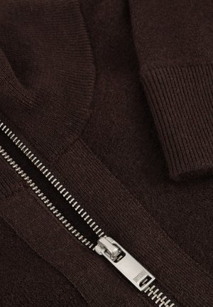 Brauner Pullover mit geripptem Kragen und Bündchen. Verfügt über einen silbernen Reißverschluss mit Zahn-Design, eine weiche Textur und eine glatte, gestrickte Stoffoberfläche.