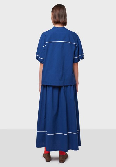 Conjunto azul de dos piezas que incluye un top corto con remates blancos y una falda larga. Diseñado en una tela suave, cuenta con mangas cortas acampanadas.