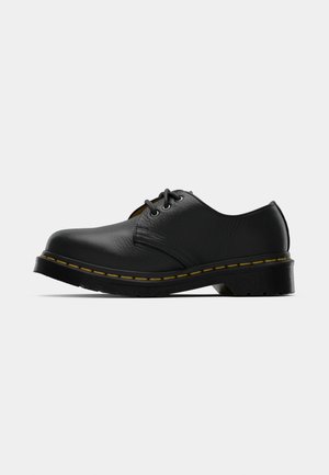 Chaussures en cuir noir avec un bout rond, un laçage, des coutures jaunes le long de la semelle, et une semelle en caoutchouc noir épaisse pour une meilleure traction.