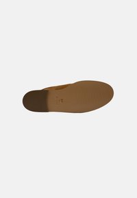 Scarpa slip-on marrone con esterno liscio, punta arrotondata, soletta imbottita e suola in gomma resistente con un motivo di grip testurizzato.