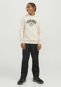 Bež hoodie s logotipom "JACK & JONES", kengurska džep, rebrasti manžeti, uparen s crnim hlačama i crnim tenisicama. Glatka tekstura tkanine.