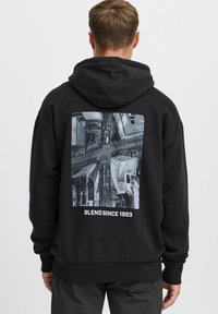 Sudadera negra con una gran impresión fotográfica aérea en gris en la parte posterior. El diseño presenta edificios urbanos y un patrón de calles, con el texto "BLEND SINCE 1993".