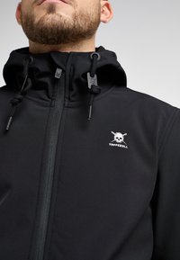 Černá zipová bunda vyrobená z měkkého materiálu Softshell. Má vysoký límec, nastavitelné šňůrky a bílou vyšitou lebku jako logo.