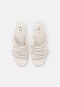 Białe wegańskie skórzane sandały na wysokim obcasie z kwadratowymi palcami, z trzema splecionymi paskami i gładką, matową teksturą.