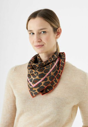 Écharpe en soie à motif léopard marron avec une bordure rouge et des accents géométriques roses, repliée en forme triangulaire, portée autour du cou.