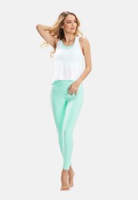 White cropped tank top paired with mint green high-waisted leggings. The leggings have a smooth, stretchy texture and a fitted silhouette.