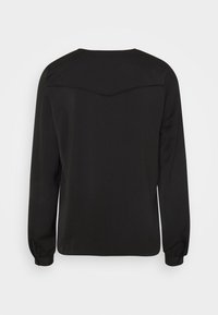 Maglietta nera a maniche lunghe con scollatura rotonda, caratterizzata da un dettaglio a yoke sulla parte superiore della schiena e polsini elasticizzati. Tessuto liscio e leggero.