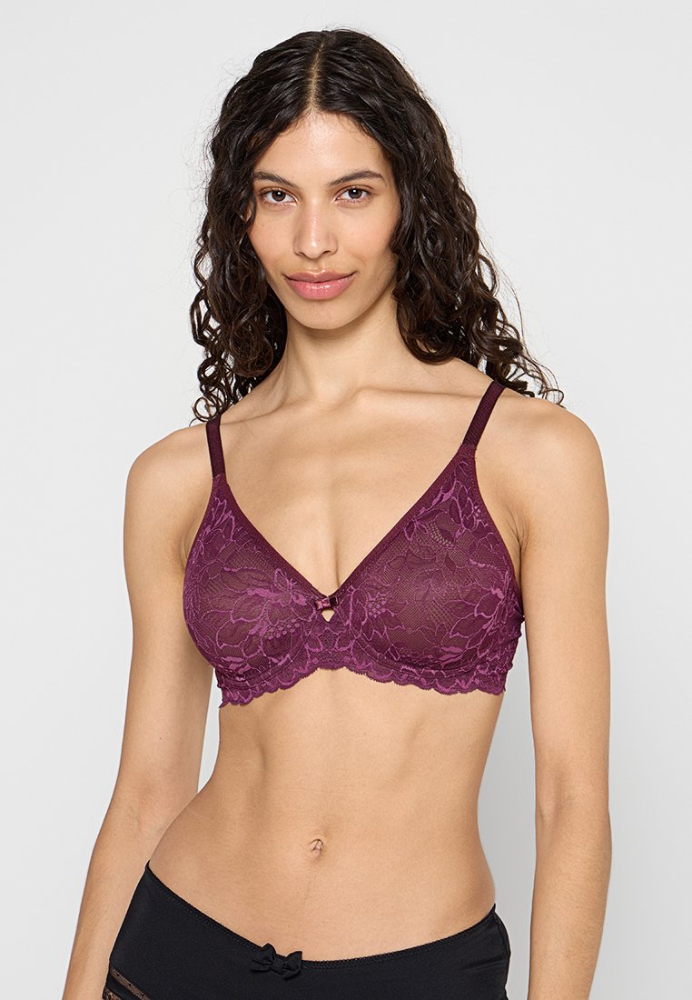 Bralette en dentelle bordeaux avec des motifs floraux, un décolleté plongeant, des fines bretelles réglables et un petit détail décoratif en métal au centre.