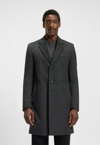 Donkergrijze wollen jas met een gesneden kraag, drie knopen, twee voorzakken en een slanke silhouet, tegen een effen achtergrond.