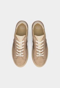 Ζευγάρι μπεζ σουέντ αθλητικά παπούτσια Nubikk με λευκά κορδόνια και πάτους Ortholite με αφρό για άνεση, σε λευκό φόντο.