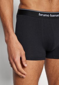 Black cotton boxer briefs with a fitted design, featuring a soft elastic waistband with white branding, and smooth, even texture.