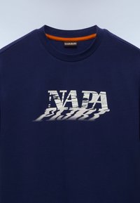 Granatowy bawełniany t-shirt z białym napisem "NAPA" z efektem cienia. Okrągły dekolt z pomarańczowym obszyciem. Krótkie rękawy. Gładka tekstura.