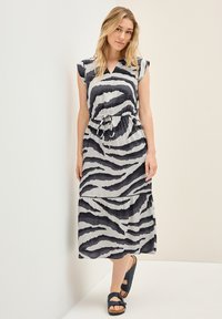 Maxikleid in Hellgrau mit schwarzen Zebra-Streifen, kurzen Kappenärmeln und verstellbarem Taillenband. Mit einem gestuften Saum und fließendem Stoff.