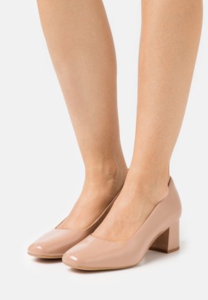 Scarpe beige in pelle vernicata con tacco a blocco e punta arrotondata, caratterizzate da una superficie liscia e da un tacco basso per una maggiore stabilità.