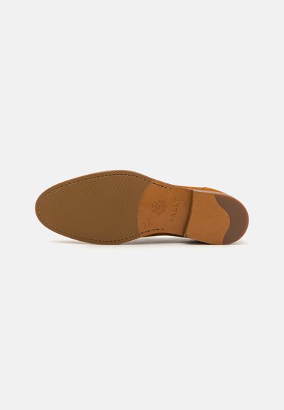 Tan leather shoe sole with a textured surface. Features a rounded toe, a prominent heel, and embossed branding near the heel.