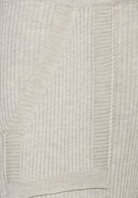 Lichtbeige gebreide trui met ribbelstructuur, voorzien van een zijzak en contrasterende stikdetails langs de naden.