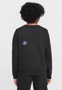 Sudadera negra con cuello redondo, manga larga y un pequeño logo de Nike en azul y naranja en la parte superior izquierda de la espalda. Textura suave, ajuste casual.