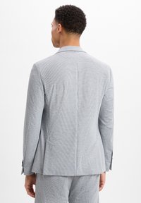 Hellgraue gestreifte Anzugjacke mit tailliertem Schnitt, einer Schlitze hinten und angedeuteten Revers. Texturiertes Gewebe und dezente Musterdetails.