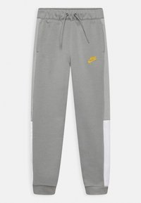 Grå sweatpants med dragsko i midjan, Nike-logotyper i gult, sidopaneler av mesh och ribbade muddar. Mjuk tygkvalitet med en avslappnad passform.