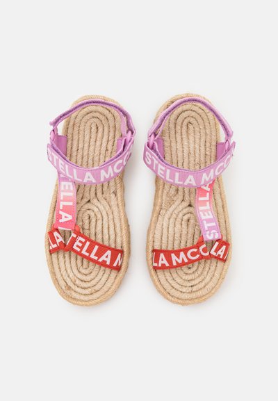 Sandale od užadi s pletenim potplatom od prirodnih vlakana, ljubičaste i crvene trake s oznakom "STELLA MCCARTNEY". Jednostavan, ravni dizajn.
