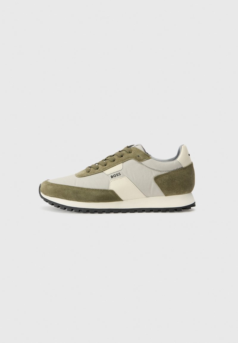 Scarpe da ginnastica verdi e beige con una combinazione di suede e tessuto, un logo bianco distintivo, suola nera piatta e lacci rotondi.