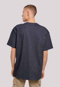 Dark navy oversized t-shirt, crew neck, short sleeves, ribbed texture, straight hem, worn with beige cargo pants.