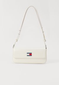 Λευκή ψεύτικη δερμάτινη τσάντα ώμου με μακρύ ιμάντα, διαθέτει μαγνητικό καπάκι και μπλε, κόκκινη και λευκή ρέλιτ σταμπαρισμένη στο μπροστινό μέρος.