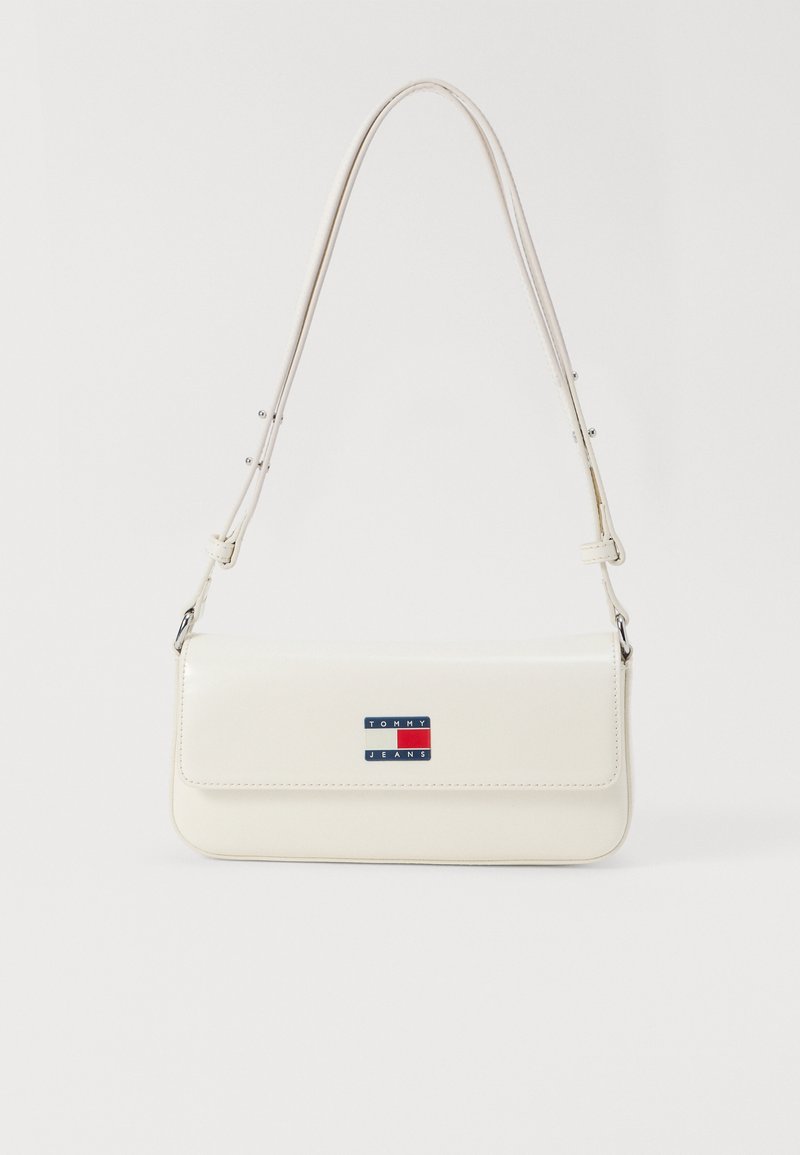 Λευκή ψεύτικη δερμάτινη τσάντα ώμου με μακρύ ιμάντα, διαθέτει μαγνητικό καπάκι και μπλε, κόκκινη και λευκή ρέλιτ σταμπαρισμένη στο μπροστινό μέρος.