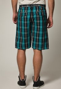 Pantaloncini a quadri con motivo nero, turchese e grigio; dotati di due tasche posteriori e passante per cintura in vita; tessuto dalla texture liscia.