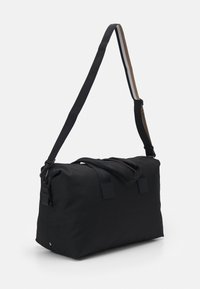 Geantă duffel din material textil negru, cu două mânere scurte și ajustabile, curea de umăr și închidere cu fermoar. Prezintă o textură uniformă și un design minimalist.