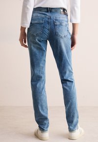 Jeans de mezclilla azul claro con un corte recto, diseño de cinco bolsillos y cintura de altura media, con un ligero desgaste y acentos cosidos.