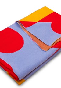 Zabawkowy koc w kolorze niebieskim z dużymi czerwonymi i żółtymi okręgami, z fakturowaną powierzchnią i kontrastującym pomarańczowym materiałem na złożonym brzegu.