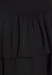 Tela negra texturizada con un diseño recogido y en capas, que presenta pequeños puntos elevados y un detalle de cintura fruncida.