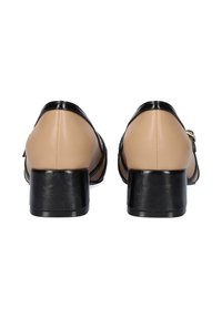 Zapatos de tacón de cuero beige con acentos de charol negro, punta redondeada y tacón cuadrado. Cuenta con una correa lateral con detalle de hardware dorado.