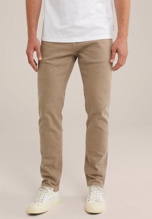 Beige bavlněné kalhoty s slim fit, pětivreckovým designem a minimálními švy, doplněné bílými šněrovacími teniskami.