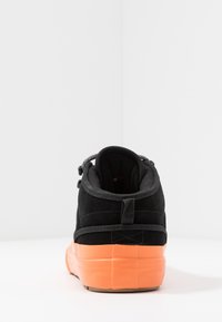 Schwarzer High-Top-Sneaker aus Wildleder mit orangefarbener Gummisohle, schwarzen Schnürsenkeln und gepolstertem Kragen. Rückansicht hebt Nahtdetails und strukturierte Akzente hervor.