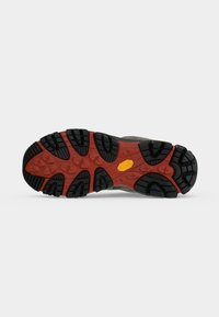 Semelle d'une chaussure de randonnée avec des crampons noirs et rouges et un logo Vibram jaune sur un fond gris clair.
