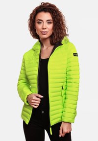 Veste matelassée vert fluo avec texture quiltée, poches zippées et capuche. Présente un intérieur noir et un logo sur la manche.
