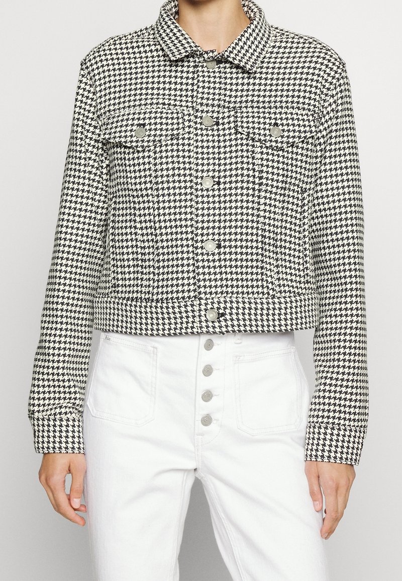 Černobílý kostkovaný zkrácený kabát s knoflíkovým zapínáním, náprsními kapsami a límcem. Nosený s bílými džíny s vysokým pasem.